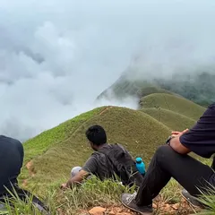 Taking a break to soak in the incredible scenery at Netravati Peak. The trek offers panoramic views of rolling green hills, often covered in a blanket of fog, creating a truly mystical atmosphere.