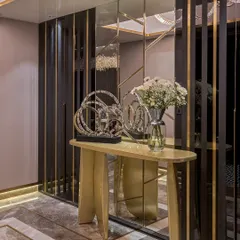 A custom console table with a unique, sculptural gold base, set against a wall of mirrored panels with brass inlays. This piece is designed to make a statement from the moment you enter a room.