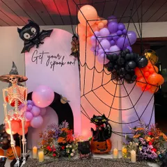 "Get your spook on!" A fun and festive Halloween party backdrop. The setup includes a giant spiderweb, a friendly skeleton, and a cascade of orange, purple, and black balloons.