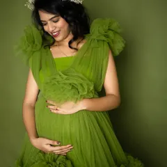 Celebrating life and growth with this beautiful mom-to-be. The vibrant green of this ruffled gown symbolizes new beginnings, perfectly complementing her radiant glow in this studio maternity portrait.