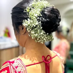 A classic bridal bun or 'juda' decorated all around with fresh baby's breath (gajra). This is a timeless and elegant hairstyle for any bride.