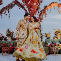 A wide shot of the couple against their stunning floral decor. The coordination of their outfits with the event's theme creates a visually breathtaking scene.
