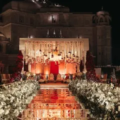 For a royal destination wedding in Jaipur, I designed this breathtaking mandap against the palace's natural architecture. The mirrored aisle reflecting the grand floral structure and ivory-and-red decor created an unforgettable, regal ambiance for the ceremony.