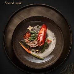 Drama served right. A beautifully cooked lobster tail is presented with fresh peas, carrots, and a delicate cream sauce, turning a classic dish into a moment of pure culinary theatre.
