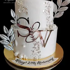 For a 25th anniversary, I designed this elegant and modern two-tiered cake. The clean white fondant, silver leaf details, and custom monogram create a sophisticated look that honours such a special milestone.