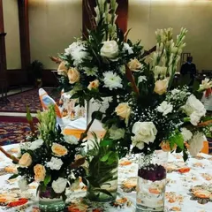A close-up of the table centerpieces for a banquet event. I used a mix of fresh white roses, tuberoses (rajnigandha), and carnations in glass vases to create a fresh and elegant look.