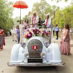 A classic groom's entry in a vintage white Rolls-Royce, a timeless and elegant choice for a grand arrival.