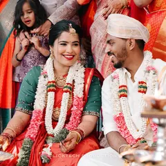 A beautiful candid shot of a South Indian bride and groom sharing a smile during their wedding ceremony, capturing the genuine happiness of the moment.