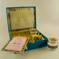 For a truly grand statement, I create custom boxed wedding invitations. This teal velvet box opens to reveal the main invitation card, separate inserts for different events, and custom-fitted compartments for gifts like dry fruits or sweets.
