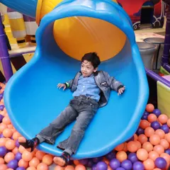 A perfect action shot of a young boy enjoying the ride down our multi-colored roller slide, landing safely in the soft ball pit below.