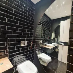 A bold and glamorous powder room with black subway tiles and a large, curved mirror that adds a dramatic touch.