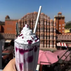 A colorful blueberry milkshake with the Hawa Mahal softly blurred in the background. This composition keeps the focus on the refreshing drink while still giving a strong sense of place.