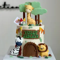 A sweet and simple jungle-themed cake for Yusuf Zuhayr. This design features a friendly lion, zebra, and giraffe around a little fondant door, perfect for a child's celebration.