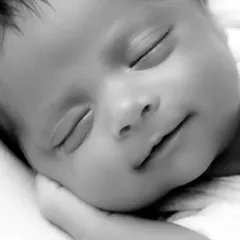 A macro shot in black and white of a newborn's face, highlighting the soft curve of their cheek and lips. This is my favorite part of newborn shoots, capturing the little details that matter most.