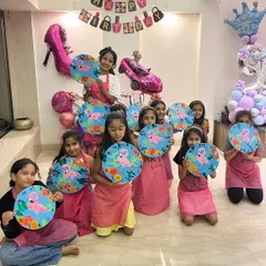 A group of happy kids proudly holding up the flamingo themed clocks they painted at Saisha's 9th birthday party. These custom art activities also double as a unique and personal return gift.