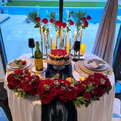 I know romance. I curate royal candlelight dinners like this one, set by a pool with a profusion of red roses and elegant tableware, perfect for an unforgettable anniversary or proposal.