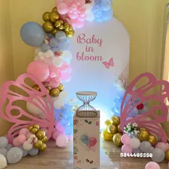 A beautiful "Baby in Bloom" baby shower with a butterfly theme. The pastel pink, blue, and gold balloon garland and large butterfly wing props create a magical and delicate setting.