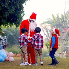 A heartwarming photo of Santa Claus interacting with three young boys in matching plaid shirts.