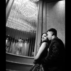 A dramatic black and white portrait under a stunning crystal chandelier. This low-angle shot creates a sense of intimacy and glamour.