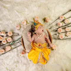 A sleepy yawn from a tiny Krishna. This is an example of our themed newborn photoshoots, where we use beautiful props like peacock feathers and soft wraps to create a magical and safe setting for your baby.