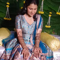 A beautiful bride in her blue lehenga, looking down at her intricate bridal mehendi. A quiet moment of admiration for the art that will be a part of her wedding day.