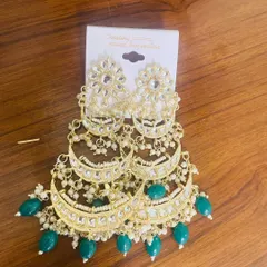 A stunning pair of green tiered chandbalis, perfect for making a statement at weddings and grand celebrations. The kundan work and green bead drops create a look of pure opulence.
