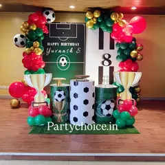 A football-themed birthday party perfect for a young sports fan. The setup includes a goalpost backdrop, trophy props, football-themed pedestals, and balloons in team colors.