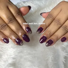 Another view of the deep plum nails with the gold glitter accent. This angle shows how the glitter catches the light, creating a beautiful contrast with the dark, glossy polish.