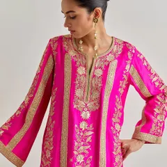 A closer look at the detailed gold floral embroidery on the fuchsia silk kurta, highlighting the craftsmanship and rich texture.