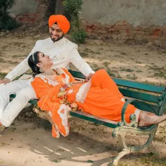 A relaxed and playful moment from a pre-wedding shoot. Having the bride lie back on a park bench while they share a laugh makes for a natural and heartwarming couple portrait.