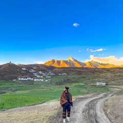On a dirt road in Spiti Valley, with the golden hour light hitting the mountains. This image captures the raw, majestic beauty of the Himalayas and the feeling of solitary exploration.