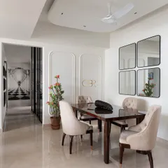 This wider view of the dining area shows its connection to the rest of the home. The design uses wall mouldings and a cluster of mirrors to add architectural interest and create an illusion of spaciousness, making it a perfect example of functional elegance.