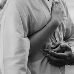 A black and white detail shot of a couple's embrace, focusing on the hands and the closeness. This image highlights the comfort and security found in a loving hug.