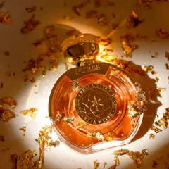 Gold. A luxurious close-up of a Guess perfume bottle, showered in gold flakes to emphasize its opulent fragrance and beautiful packaging. The lighting creates a warm, radiant glow.