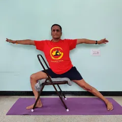 Veerabhadrasana 2 (Warrior 2) practiced on a chair. This variation is excellent for understanding the rotation of the torso and the alignment of the arms and legs while supporting the hips.
