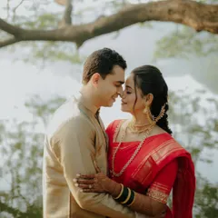 An intimate portrait by the water. The couple's closeness and the soft, natural lighting create a romantic and serene atmosphere, highlighting the elegance of their traditional Maharashtrian wedding attire.