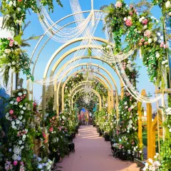 A fairytale entrance for a daytime wedding. Golden arches are adorned with lush florals and hanging crystal strings, creating a beautiful play of light and color as guests walk through.