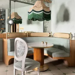 A custom-upholstered chair with a classic silhouette sits beside a curved booth. The mix of gingham and floral-patterned fabrics demonstrates our approach to layering patterns in a subtle, sophisticated way.
