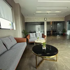 The waiting area for the M/s ALP office in Ambala, featuring a mix of houndstooth and leatherette sofas. The nested coffee tables with marble tops and brass frames add a touch of luxury to the professional setting.