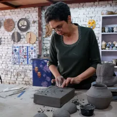 A student intently works on a slab-built piece, pressing textures into the clay. My workshops cover a range of hand-building and sculpting techniques.