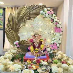 This modern Ganpati decor combines traditional flowers with contemporary elements. A beautiful crescent of white and pink flowers is accented with large, golden dried palm leaves, creating a stylish and sophisticated look for the festival.