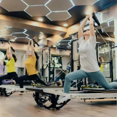 A synchronized group lunge sequence in action. This exercise not only strengthens the legs but also improves posture and coordination as everyone moves together on their Reformers.