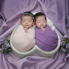 A perfectly symmetrical portrait of the newborn twins. This shot showcases the careful posing and styling involved in a twin photoshoot to create a balanced and artistic image.