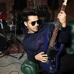 Capturing Varun Dhawan's rockstar persona. This shot places him in a studio setting with a guitar, creating a relaxed yet cool image that feels like a candid moment from a jam session.