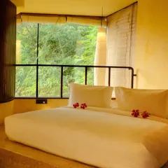 A cozy, sunken bed nook with a large window looking out into the dense greenery, making you feel completely immersed in nature.