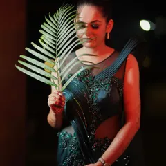 An elegant and moody solo portrait of the bride-to-be. The creative use of a palm leaf and soft red lighting adds an artistic touch, highlighting her grace and anticipation before the wedding.