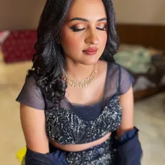 An elegant and modern reception look featuring a navy blue lehenga. The makeup is soft and glamorous with a neutral lip, paired with crimped waves for a chic hairstyle.