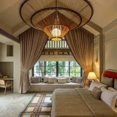 A bedroom should be a sanctuary. In this high-ceilinged suite from the 'Summer Haus' project, a dramatic, oversized rattan chandelier becomes the centerpiece, creating a sense of warmth and grandeur. The design balances impressive scale with intimate details like the cozy bay window seating.