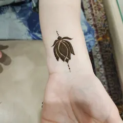 A small, symbolic lotus bud on the wrist. This is a perfect example of a modern, minimalist henna tattoo.