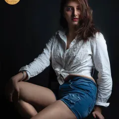 A classic studio portrait for a model's portfolio. The simple white shirt and denim shorts look is timeless, and the lighting is crafted to create a bold and confident image.